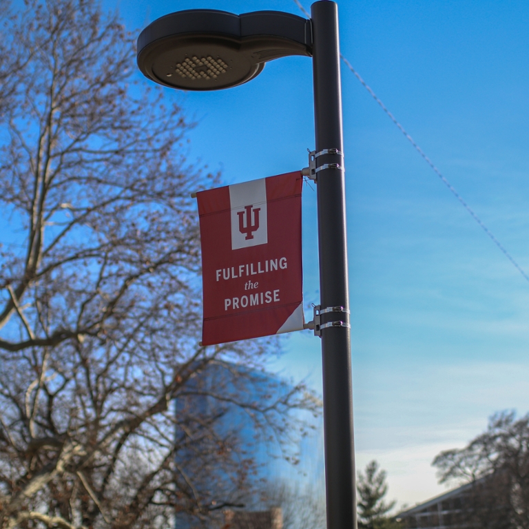 Light post with IUPUI branded sign attached. Sign says Fulfilling the Promise
